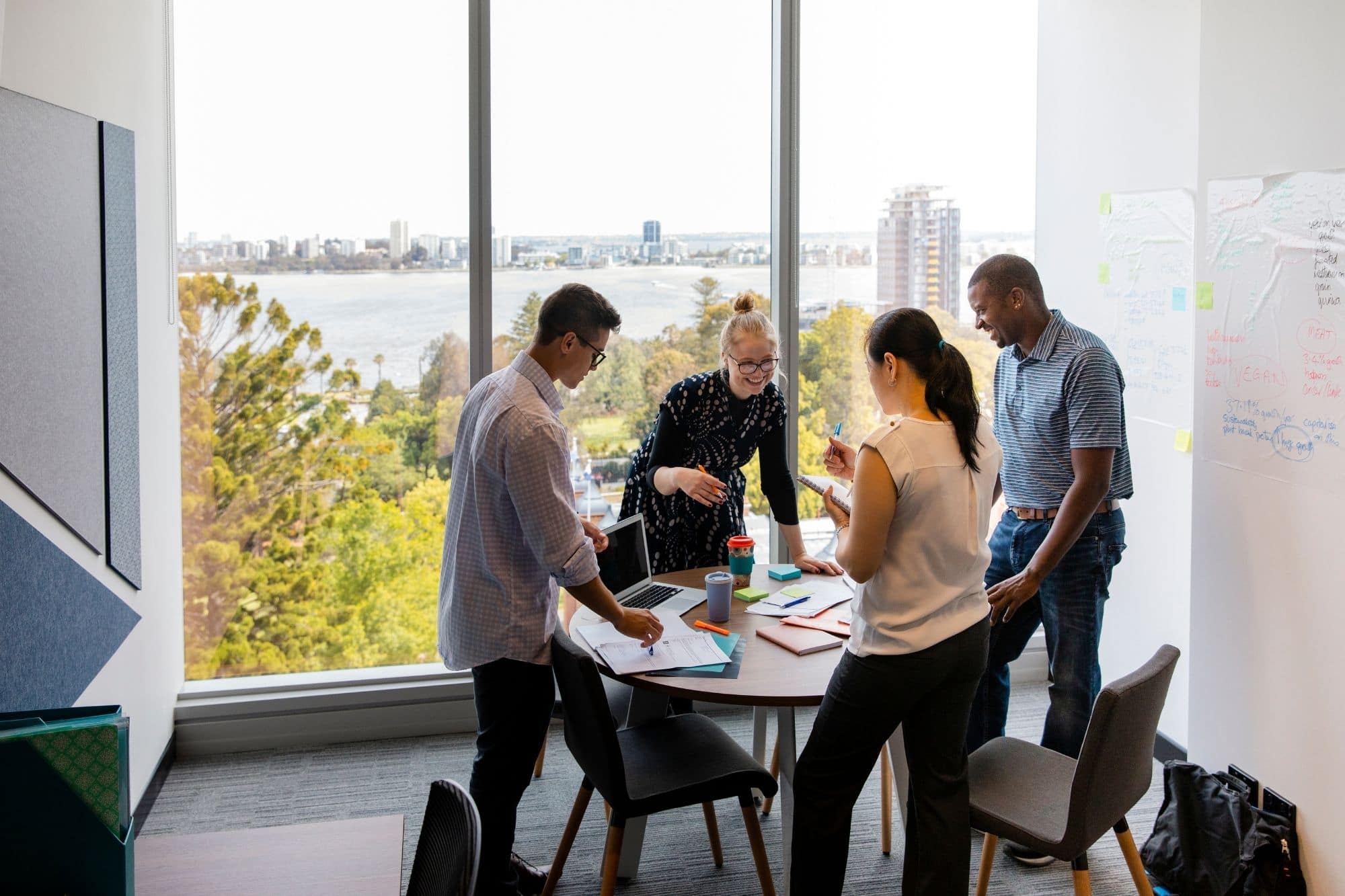 A team of people working together at a table- open windows behind them for Scion Staffing the Award-Winning San Francisco Recruiting Agency